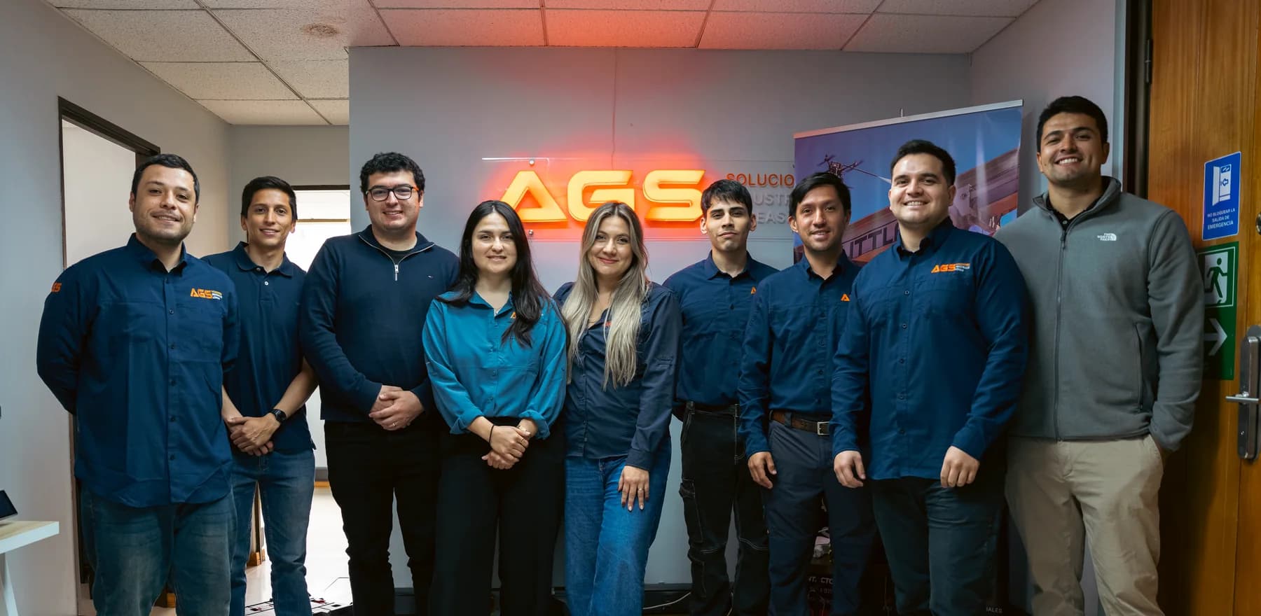 The AGS Soluciones team gathered in front of the company sign at their offices