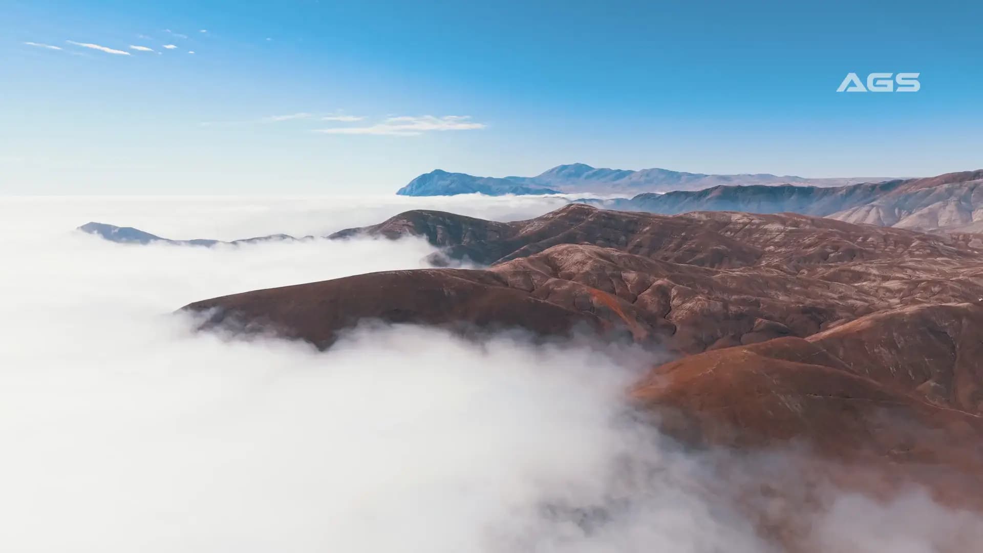 Aerial view of desert hills rising above a sea of clouds