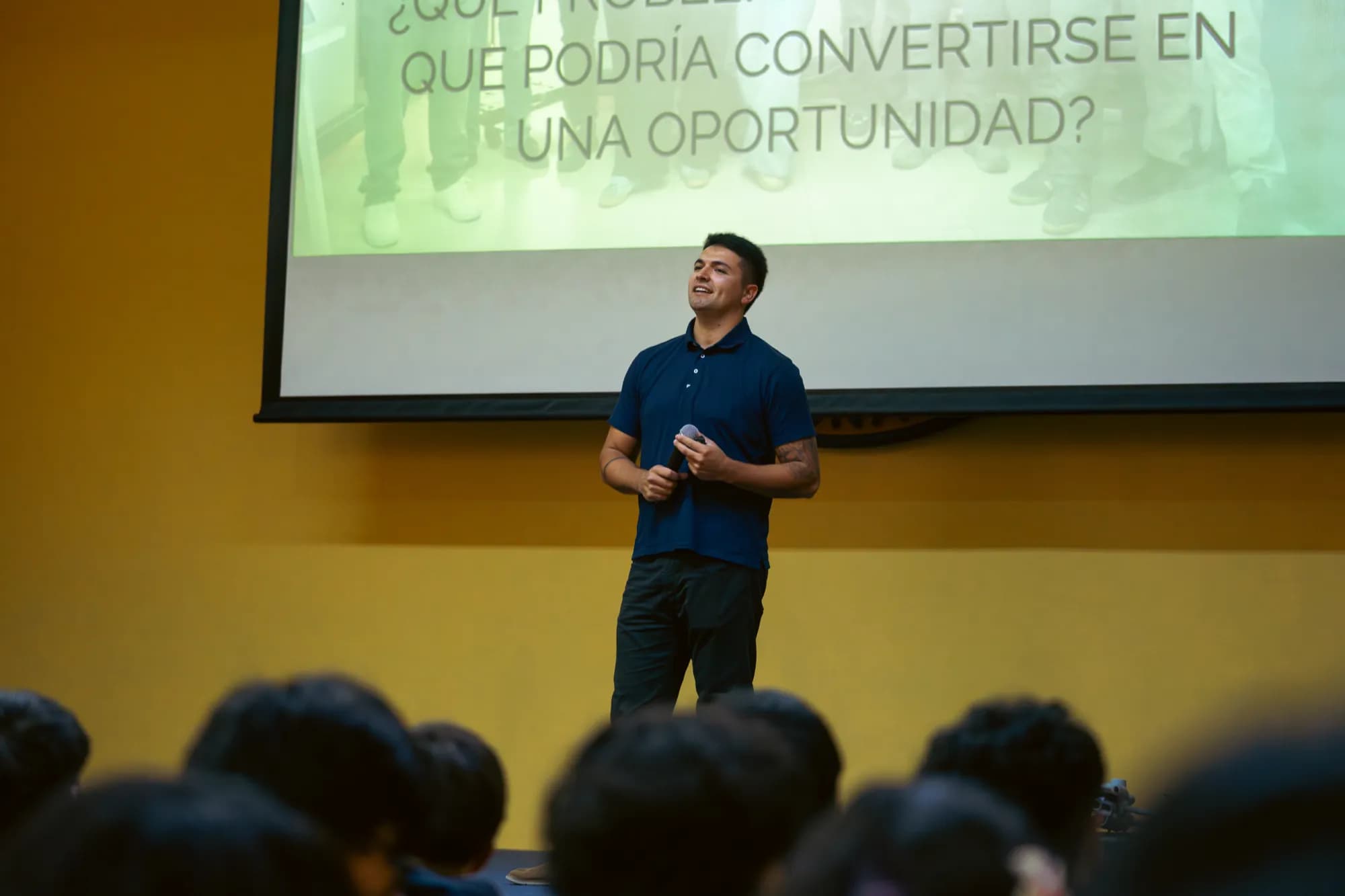 Christian Cubelli of AGS speaking on the stage of the AIS school auditorium in front of the audience