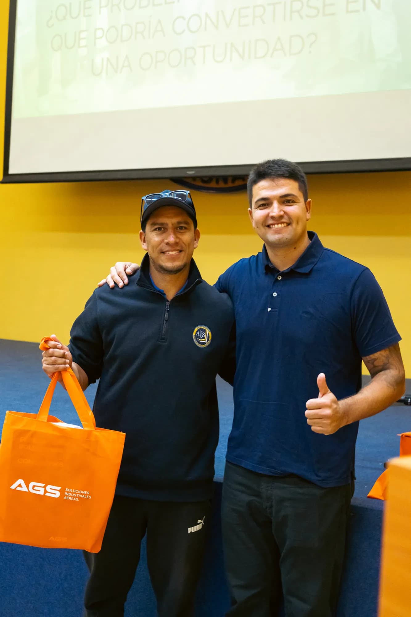 Christian Cubelli junto a un profesor del colegio AIS, con una bolsa de AGS, al término de la charla