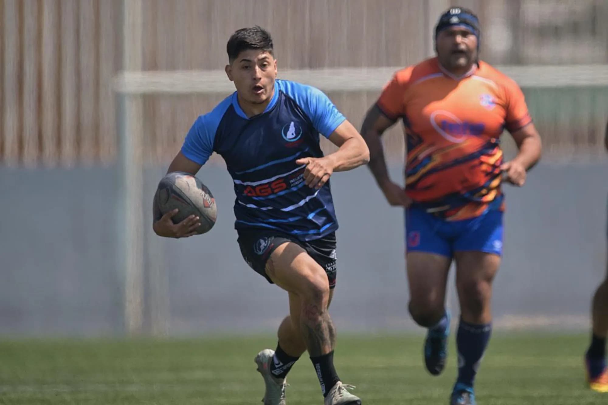 A Coyotes Antofagasta player running with the ball during a match, in the AGS-sponsored jersey